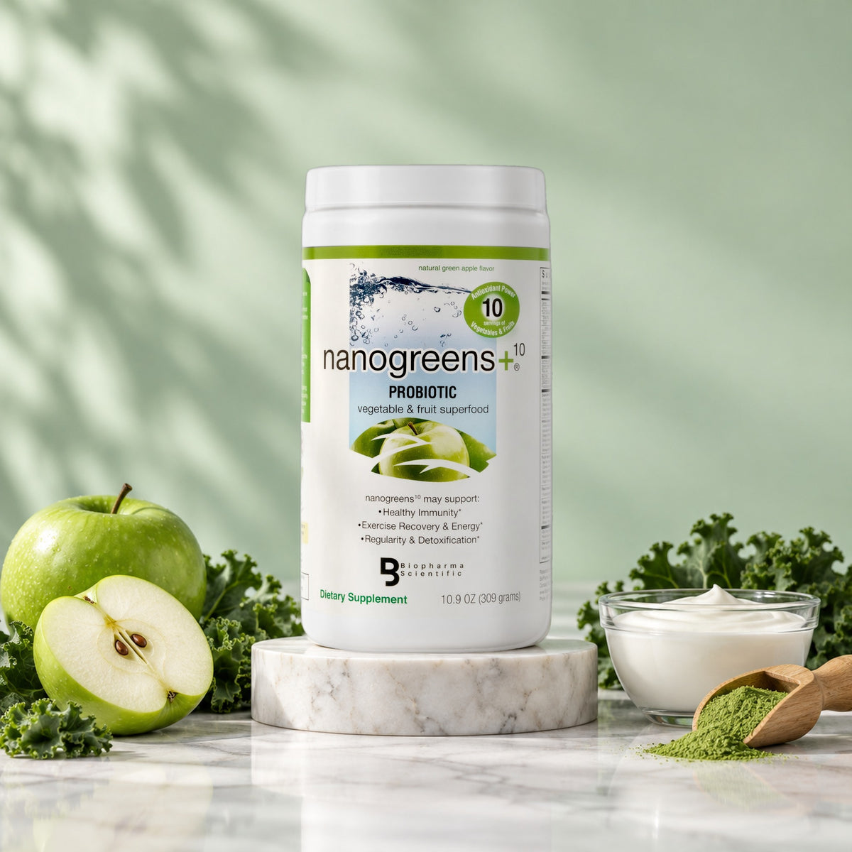 NanoGreens10+ Probiotic Green Apple tub in a bright studio still life with fresh ingredients